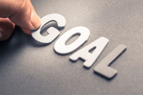 Hand placing the letter "G" to spell out "GOAL" on a textured surface.